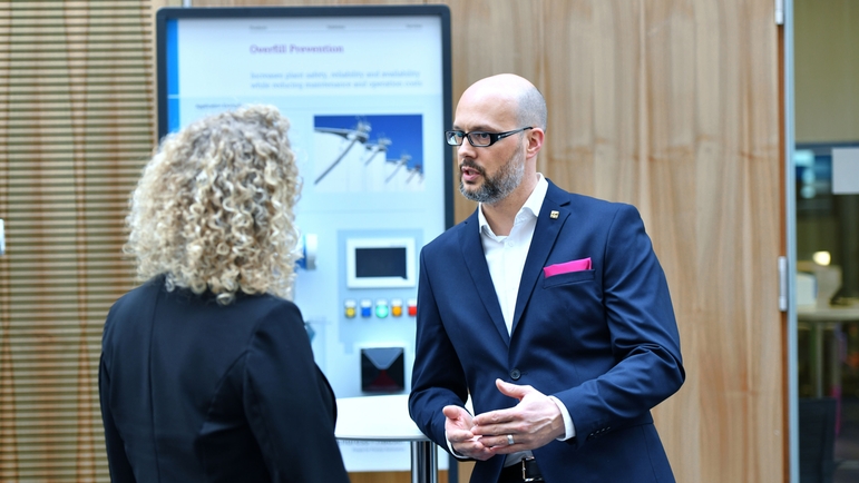 Employee and customer discussing in front of a exhibit at a seminar