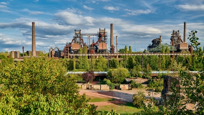 Stahlwerk inmitten einer grünen Landschaft.