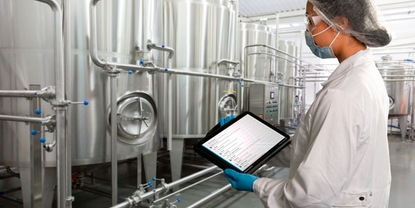 Woman standing in Food & Beverage production facility and checking the Netilion Asset Health status