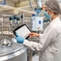 Mitarbeiterin mit Tablet, auf dem Netilion Asset Health installiert ist, vor in einer Produktionslange