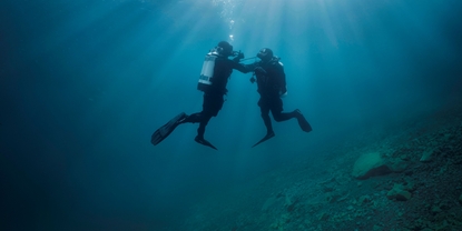 Onderwaterscène: een duiker ondersteunt een tweede duiker die problemen heeft met zijn luchtvoorziening.